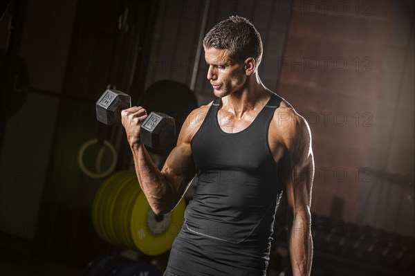 Caucasian man lifting dumbbell in gymnasium