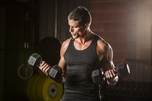 Caucasian man lifting dumbbells in gymnasium