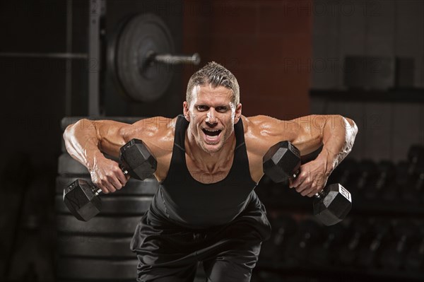 Caucasian man lifting dumbbells in gymnasium