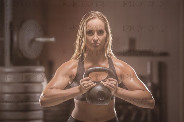 Caucasian woman lifting kettlebell in gymnasium