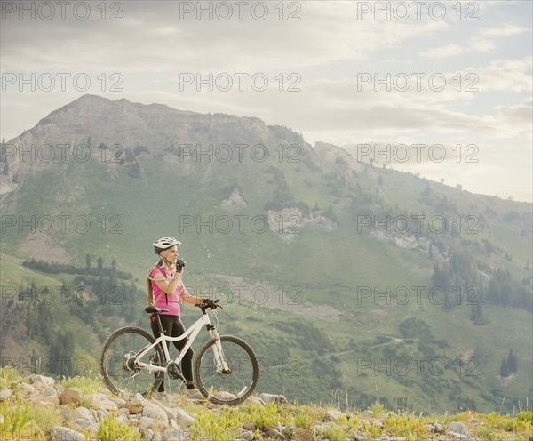 Caucasian woman with mountain bike drinking from backpack