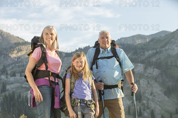 Caucasian grandparents and granddaughter hiking on mountain