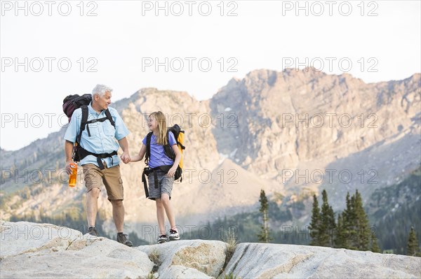 Caucasian grandfather and granddaughter hiking on mountain