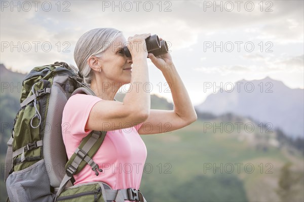 Caucasian woman hiking on mountain using binoculars