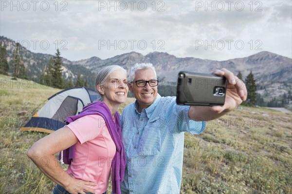 Caucasian couple posing for cell phone selfie on mountain