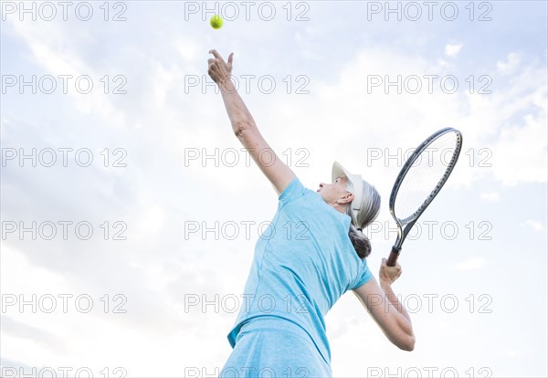 Caucasian woman serving tennis ball
