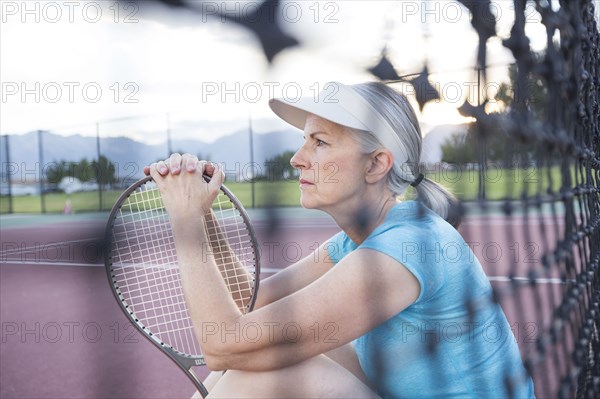 Caucasian woman resting and holding tennis racket