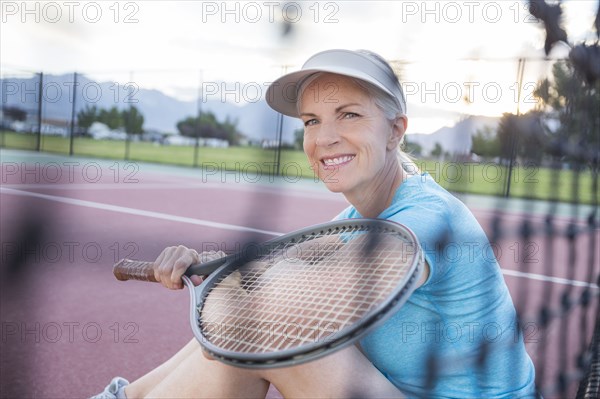 Caucasian woman resting and holding tennis racket