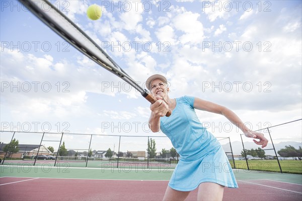 Caucasian woman hitting tennis ball
