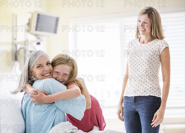 Caucasian granddaughter hugging grandmother in hospital