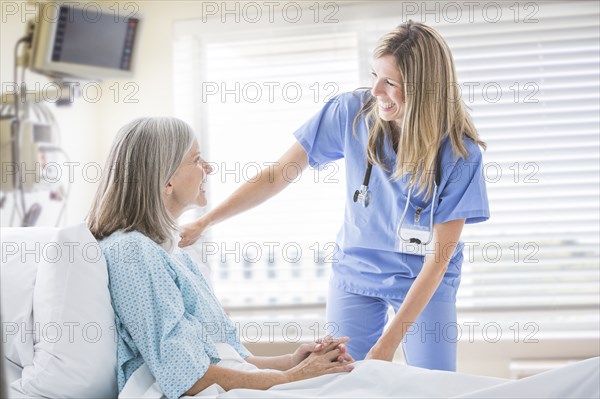 Caucasian nurse talking with woman in hospital bed