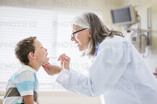 Caucasian doctor examining mouth of boy