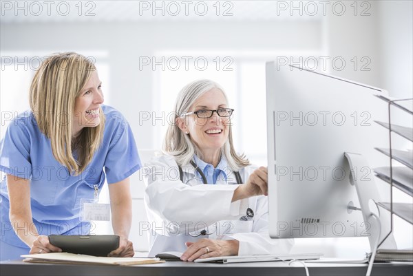 Caucasian doctor and nurse using computer at desk