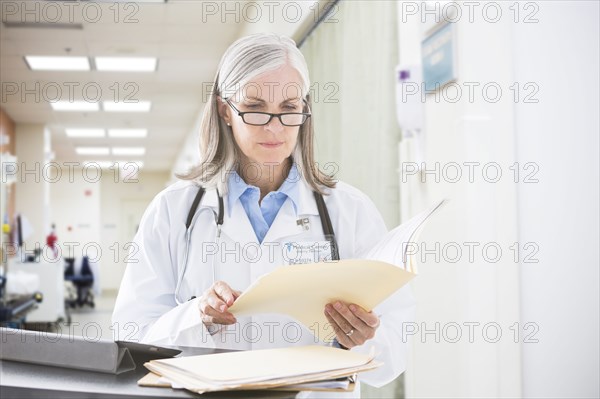 Caucasian doctor reading files in hospital