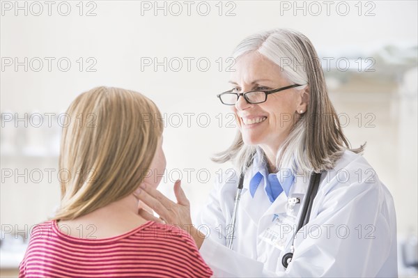 Caucasian doctor checking neck of girl