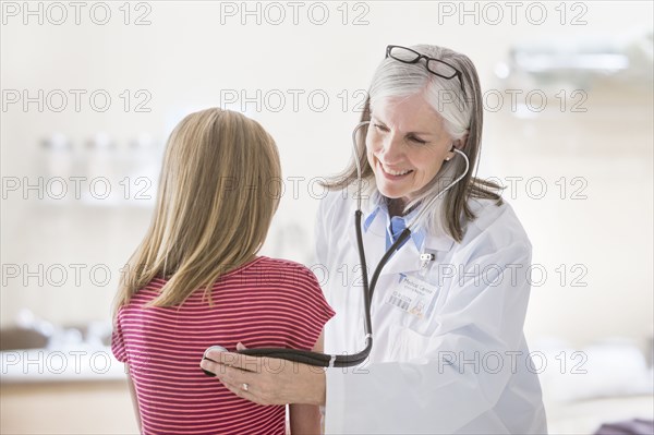 Caucasian doctor listening to chest of girl