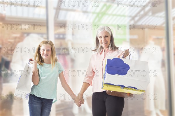 Portrait of Caucasian grandmother and granddaughter holding shopping bags