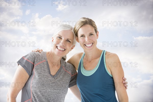 Smiling Caucasian women hugging against clouds