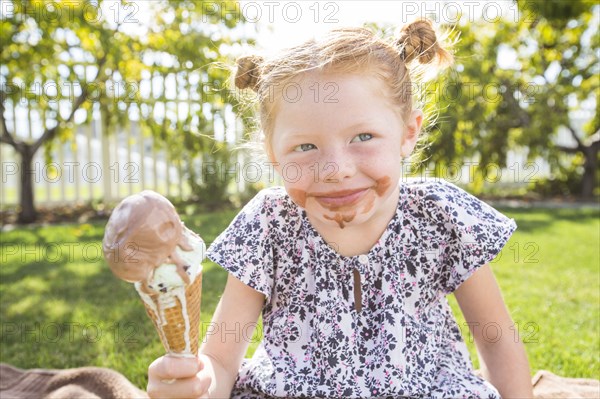 Caucasian girl with messy face eating ice cream cone