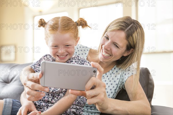 Caucasian mother and daughter posing for cell phone selfie