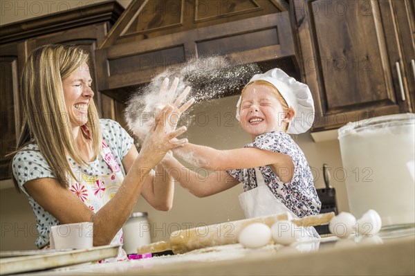 Caucasian mother and daughter having food fight with flour