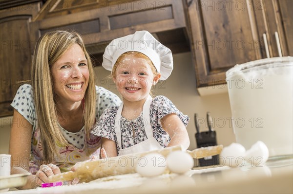 Caucasian mother and daughter covered in flour from food fight