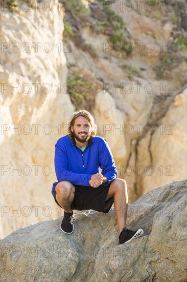 Caucasian man crouching on rock formation