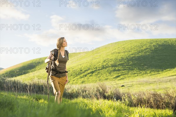 Caucasian woman holding walking stick on hill