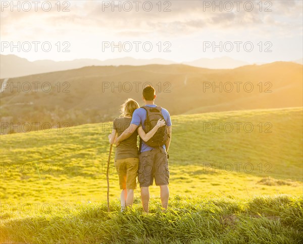 Caucasian couple hugging on hill
