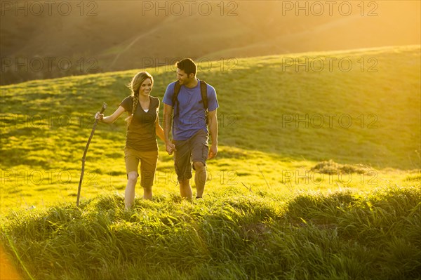 Caucasian couple hiking on hill