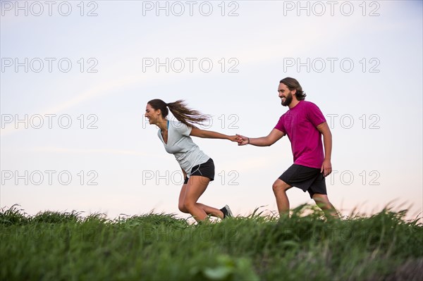 Caucasian woman pulling man on hill