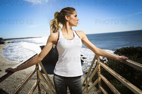 Caucasian woman standing on staircase at beach