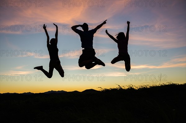 Silhouette of friends jumping for joy at sunset