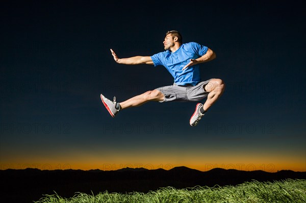 Caucasian man jumping at sunset