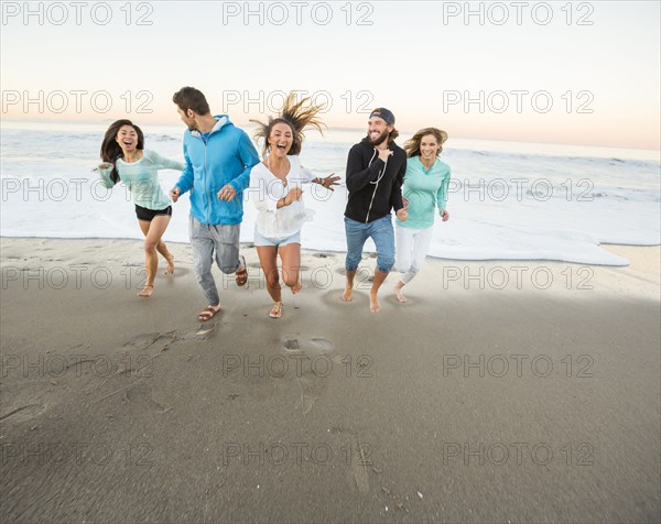 Smiling friends running on beach