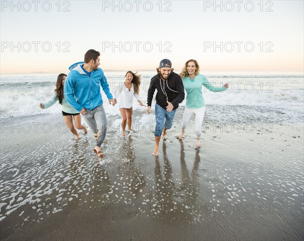 Smiling friends running on beach