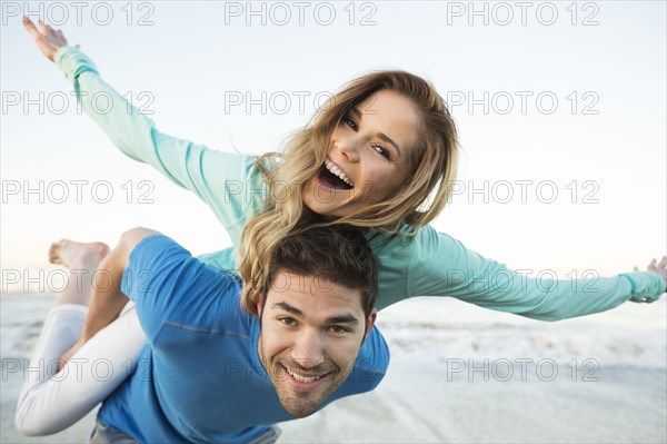 Man carrying woman piggyback at beach