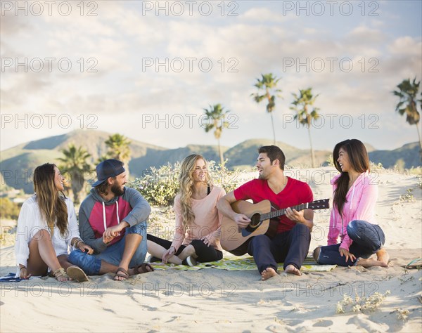 Man playing guitar for friends at beach