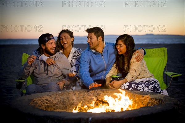 Couple relaxing on beach at fire pit