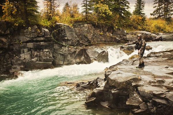 Caucasian man casting at river