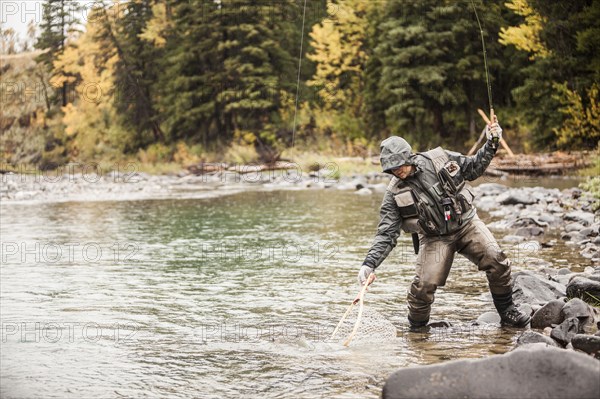 Caucasian man fishing in river holding net