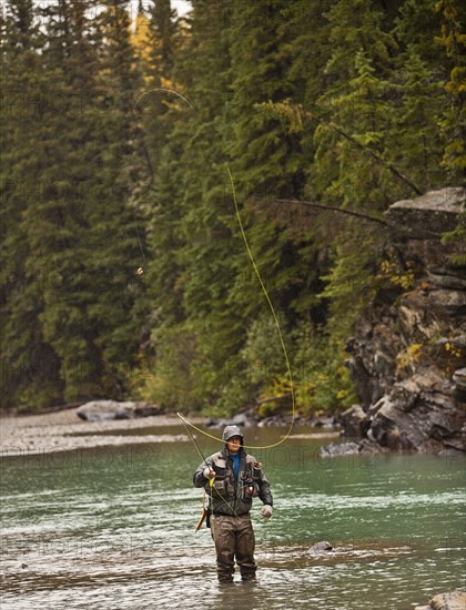 Caucasian man casting in river