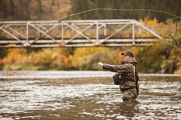 Caucasian man casting in river