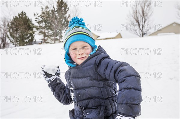 Smiling boy throwing snowball in winter