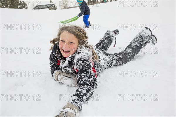 Laughing girl laying in snow in winter