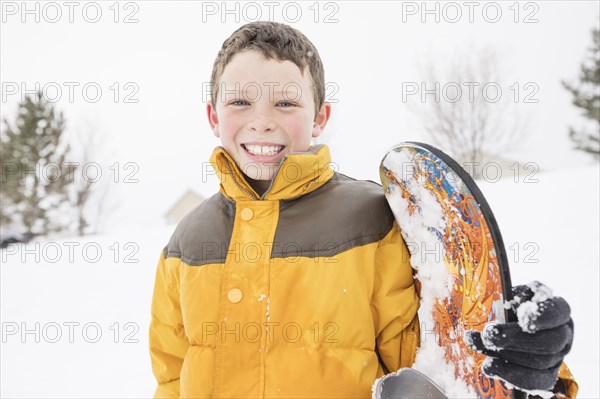 Smiling boy posing with snowboard in winter