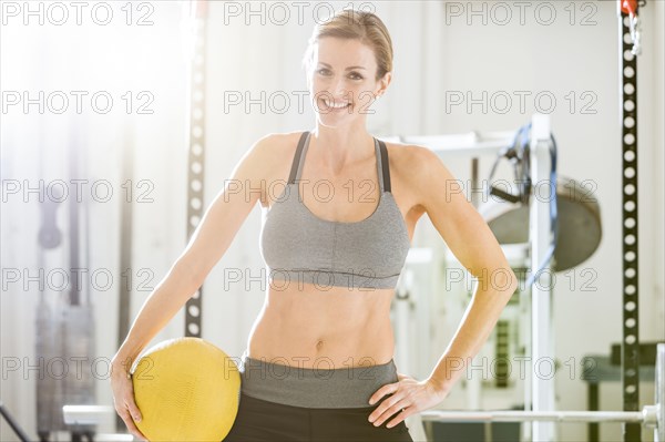 Woman holding heavy ball in gymnasium