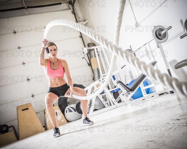 Woman lifting heavy ropes in gymnasium