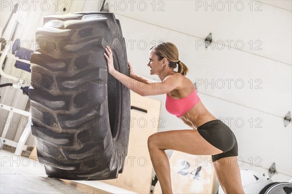 Woman pushing heavy tire in gymnasium