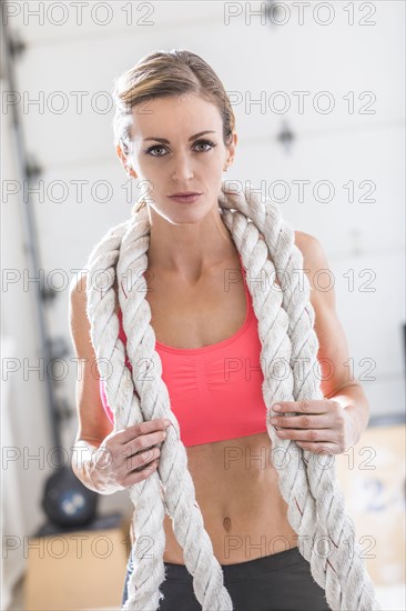 Woman holding heavy ropes in gymnasium